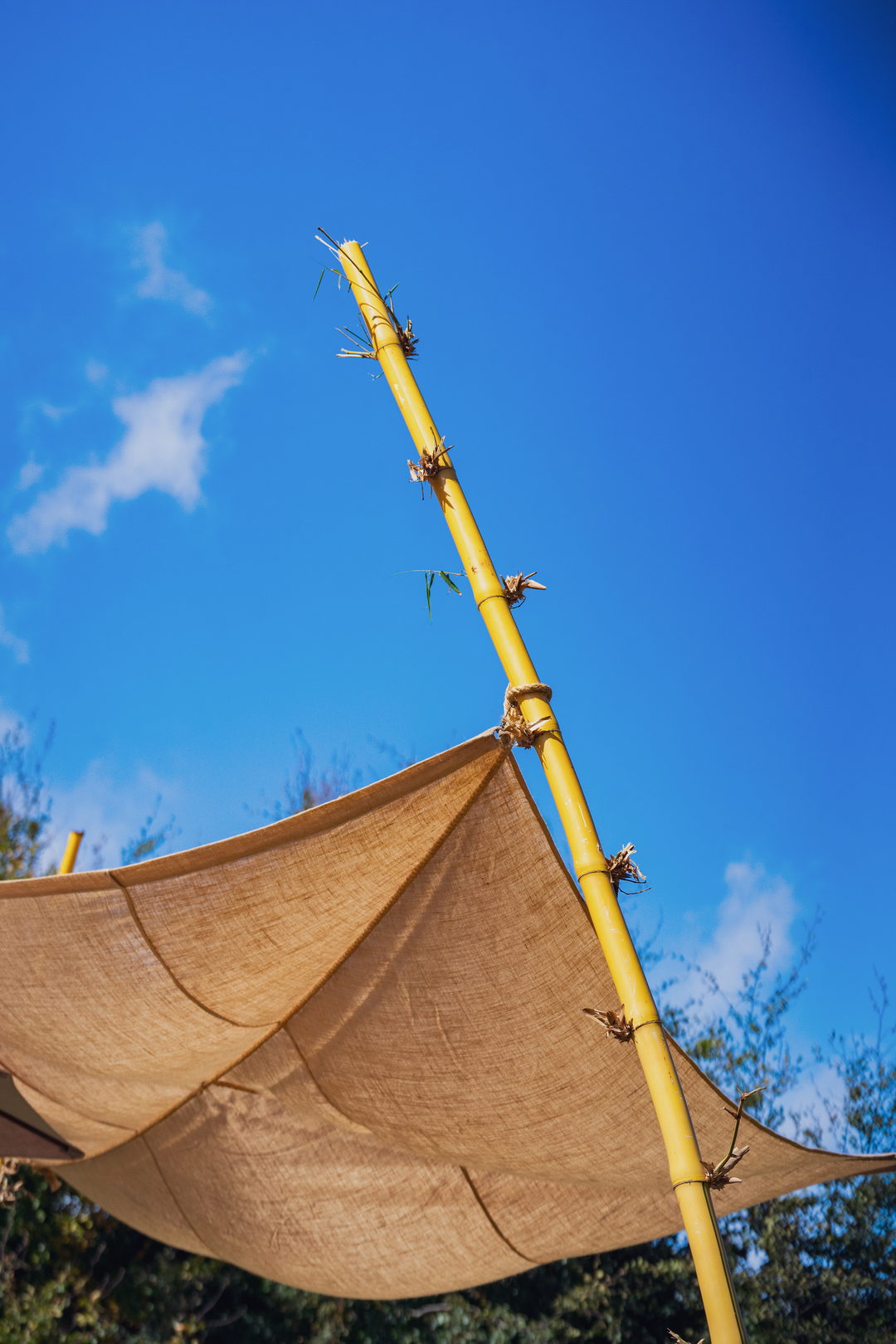 Vela de tecido presa a um mastro de bambu, contra o céu azul do Chão das Feiteiras.